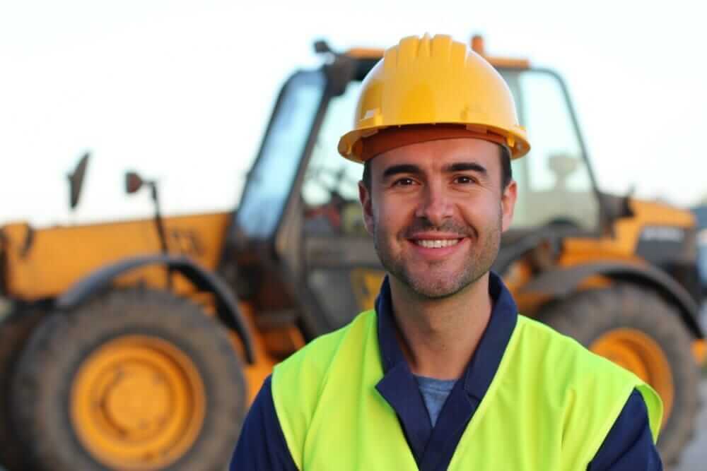 Heavy-machine-med (1) Construction worker smiling infront of a excavator